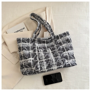 Macro shot of large black and white houndstooth tote bag with dual straps and tweed fabric