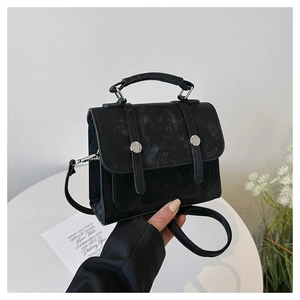 Detailed macro view of black vintage textured faux leather handbag with silver buckles