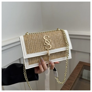 Detail of woven straw crossbody bag with white leather trim and gold tassel logo