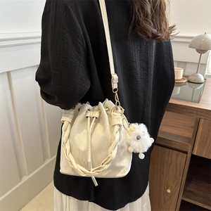 Sac seau minimaliste crème avec poignée tressée et charmant pendentif en peluche