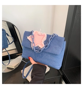 Close-up of denim crossbody bag featuring a pink frayed star patch and plastic chain