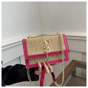 Detail of woven straw flap bag with rose pink leather trim and gold chain strap