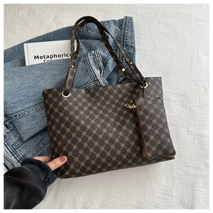 Detailed view of brown monogram tote bag with matching zipper pouch on textured background
