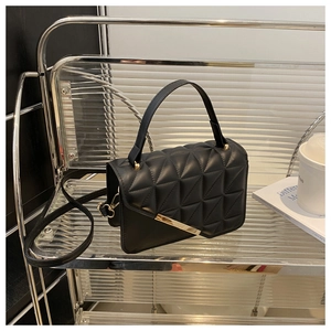 Dettaglio della borsa nera trapuntata con finiture in metallo dorato e texture pelle