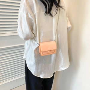 Petit sac bandoulière brillant abricot avec chaîne argentée porté par un mannequin