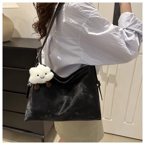 Close-up of black leather tote bag with cloud pendant worn over the shoulder