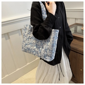 Detail of blue and white tweed tote bag showing fabric texture and shoulder drape