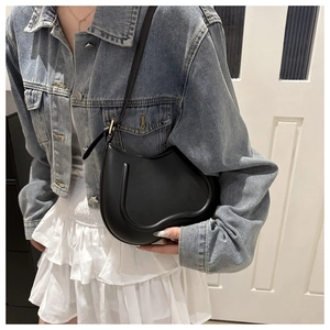 Detail of a black heart-shaped leather shoulder bag with unique U-shaped groove decoration