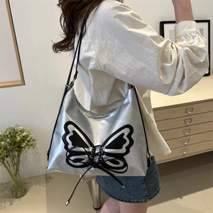 Silver metallic shoulder bag with black butterfly embroidery on model in a modern room