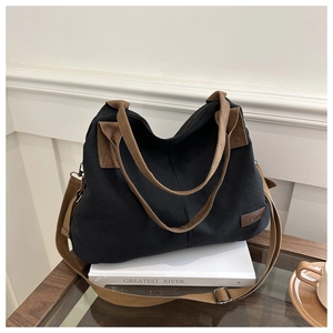 Detail of canvas tote bag with brown straps, fashion leather patch, and removable shoulder strap