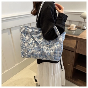 Modern large capacity tote bag with blue houndstooth pattern shown on model's shoulder