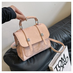 Close-up of pink suede crossbody bag with flap cover and metallic silver studs