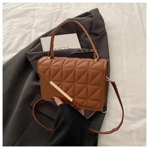 Dettaglio della borsa marrone trapuntata in ecopelle con barra dorata e manico elegante
