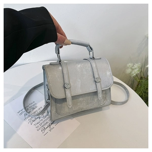 Detail of silver textured leather handbag with dual straps and metallic buckle accents