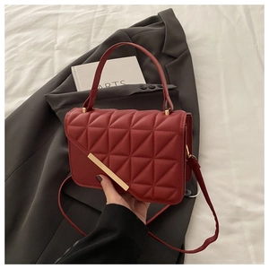 Dettaglio ravvicinato di una borsa a tracolla rossa con motivo trapuntato geometrico