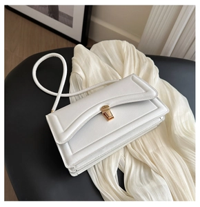 Detail of white leather small crossbody bag featuring a golden metal buckle and textured flap