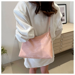 Pale pink minimalist crossbody bag shown worn by a model in a cozy indoor setting