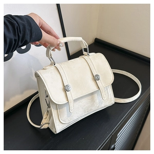 Detail of cream suede tote bag with silver buckle straps and top handle for women