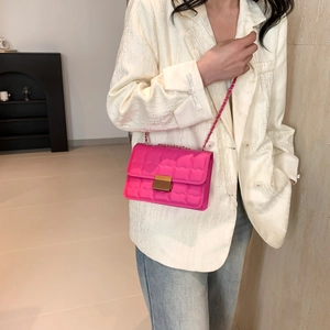 Pink quilted crossbody bag with gold chain strap worn by a model in casual chic attire