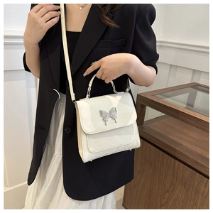 Detail of a beige marble pattern handbag with a silver butterfly clasp and shoulder strap