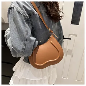 Close-up of caramel leather shoulder bag showing structural U-shaped embossed seam detail