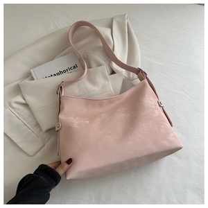 Pink suede hobo bag with vintage texture and adjustable strap on neutral background