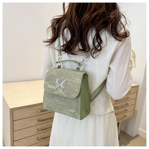 Detail of light green pleated PU leather backpack with a silver butterfly metal buckle