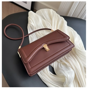 Close-up of brown faux leather flap bag with decorative stitching and gold metal buckle lock