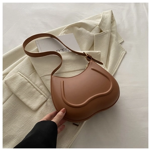 Detail of brown leather handbag with U-shaped embossed lines on beige blazer background