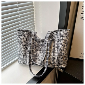 Close-up of black and white tweed tote bag showing textured fabric and natural light