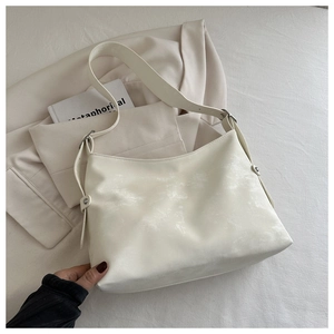 Detail of a minimalist beige tote bag with a wide strap and polished silver metal buckle