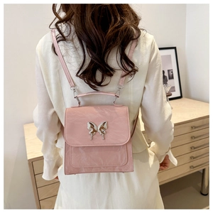 Close-up of pink crinkled leather mini backpack featuring a metallic butterfly clasp