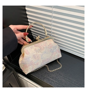 Close-up of vintage floral brocade bag with golden metal frame and circular handle