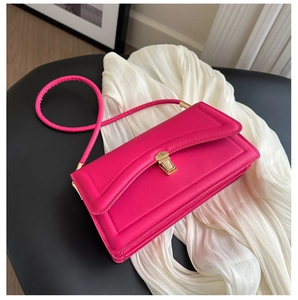 Close-up of fuchsia square crossbody bag featuring a golden square push-lock and leather strap