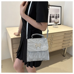 Detail of silver butterfly hardware on a textured grey crossbody bag for women