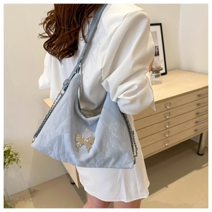 Détail du sac à bandoulière bleu clair avec boucle papillon argentée et texture
