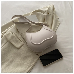 Close-up of cream curved shoulder bag featuring fine leather texture and golden metal buckle