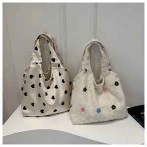Détail d'un sac cabas en satin à cœurs et d'un sac à main en peluche à fleurs colorées