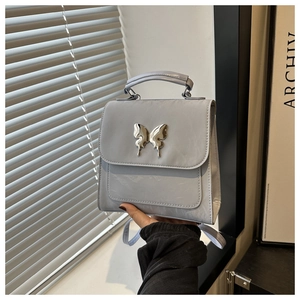 Close-up of light gray PU leather handbag featuring a silver butterfly metal buckle
