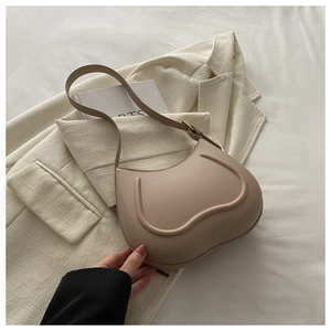 Close-up of beige minimalist underarm bag with heart-shaped embossed curve on a blazer