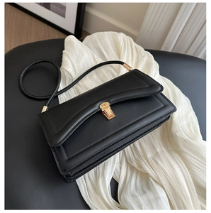 Detail of minimalist black leather crossbody bag with elegant gold metal clasp closure