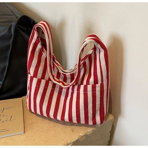Detail of red and white striped canvas tote bag showing the textured fabric and front pocket