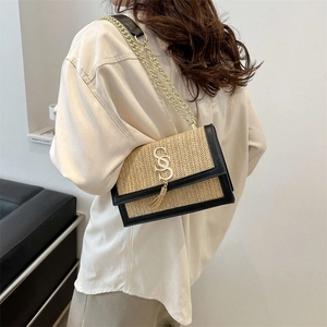 Fashionable woven straw shoulder bag with gold S-buckle and tassel on a female model