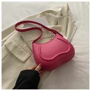 Detailed view of magenta crescent bag with U-shaped ridges on a beige tweed blazer