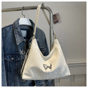 Détail d'un sac hobo blanc texturé avec boucle papillon argentée et bandoulière chaîne