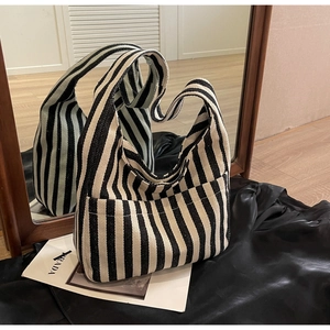 Macro detail of black and white striped woven tote bag with wide integrated handle