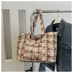 Detail of vintage plaid tote bag hanging with denim jacket in a lifestyle setting