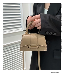 Detail of a shiny beige patent leather mini tote bag with a sleek flap and top handle