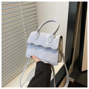 Detail of light blue crossbody bag featuring wavy scalloped edges and gold metal hardware
