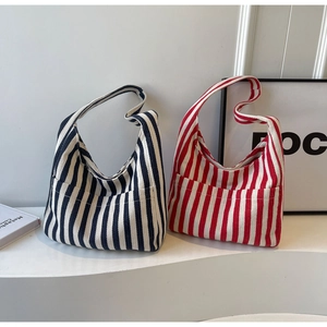 Detail of navy and red striped canvas tote bags with front pockets on white stand